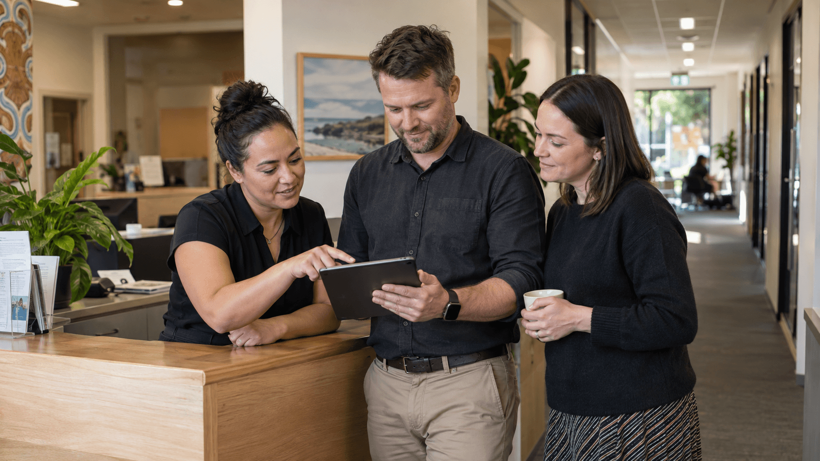 Three colleagues reviewing a tablet together in a community-services workplace