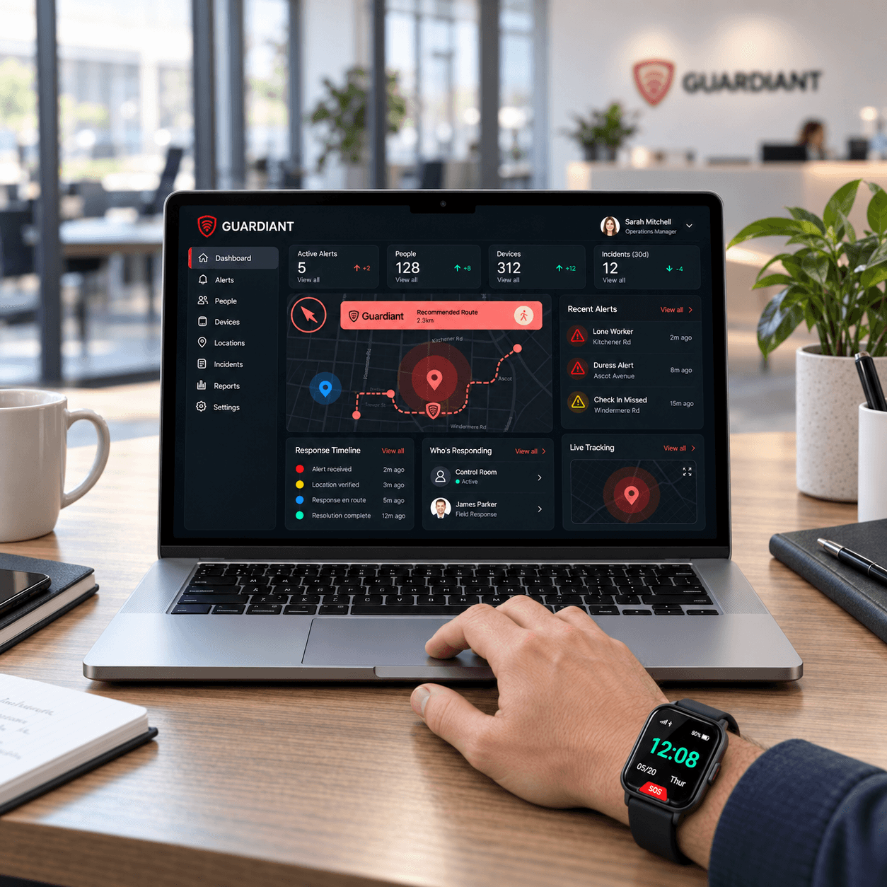 An employee wearing a Guardiant watch uses the Portal dashboard on a laptop at a workplace desk